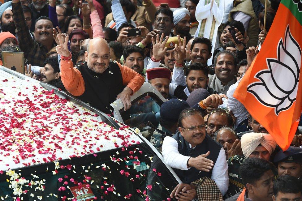 BJP president Amit Shah shows the victory sign to supporters as he arrives to at the party headquarters in Delhi