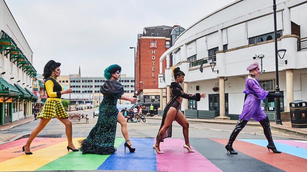 Drag artists standing on rainbow crossing