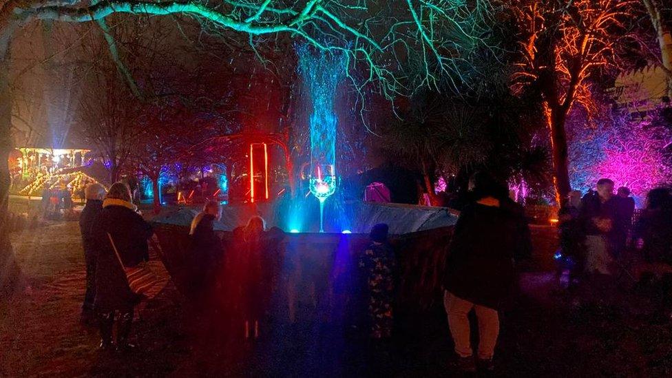 Crowds looking at a wine glass shaped light sculpture