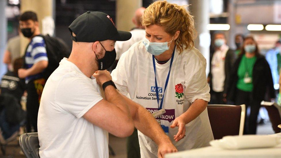 A man is given a vaccine by a volunteer at Twickenham stadium