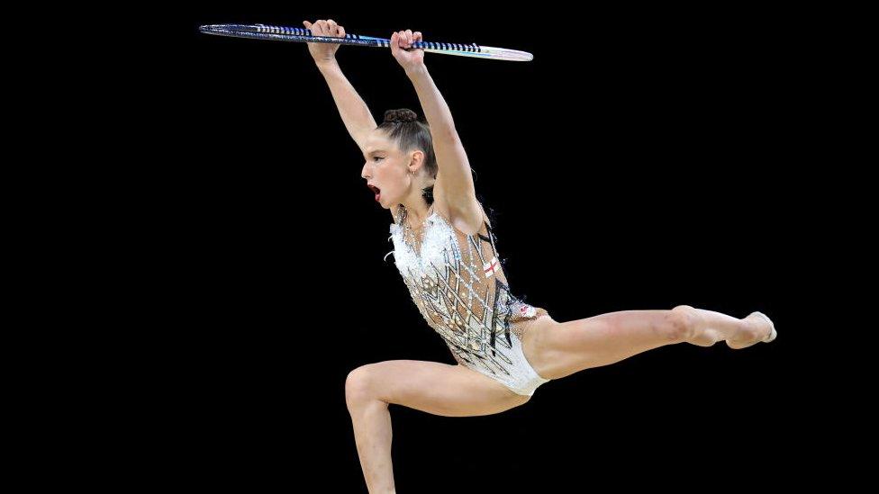 Marfa Ekimova leaping through the air performing with a hoop