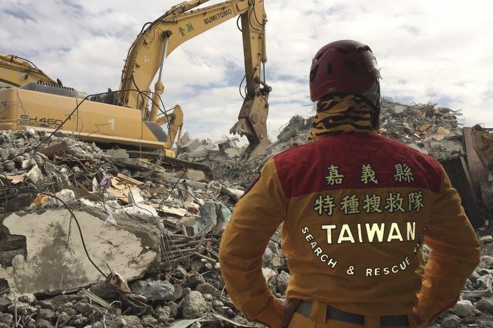 A rescue worker watches a digger at the collapsed building in Tainan, Taiwan (11 Feb 2016)
