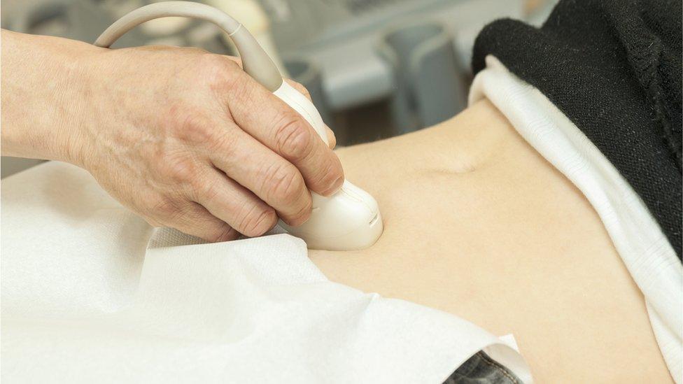 Woman having her abdomen examined