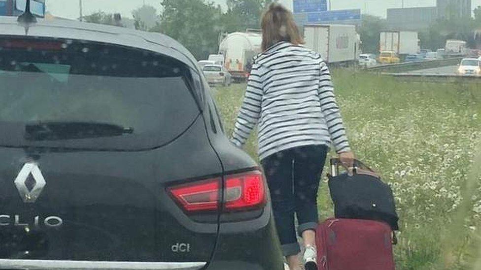 woman walks along road with luggage