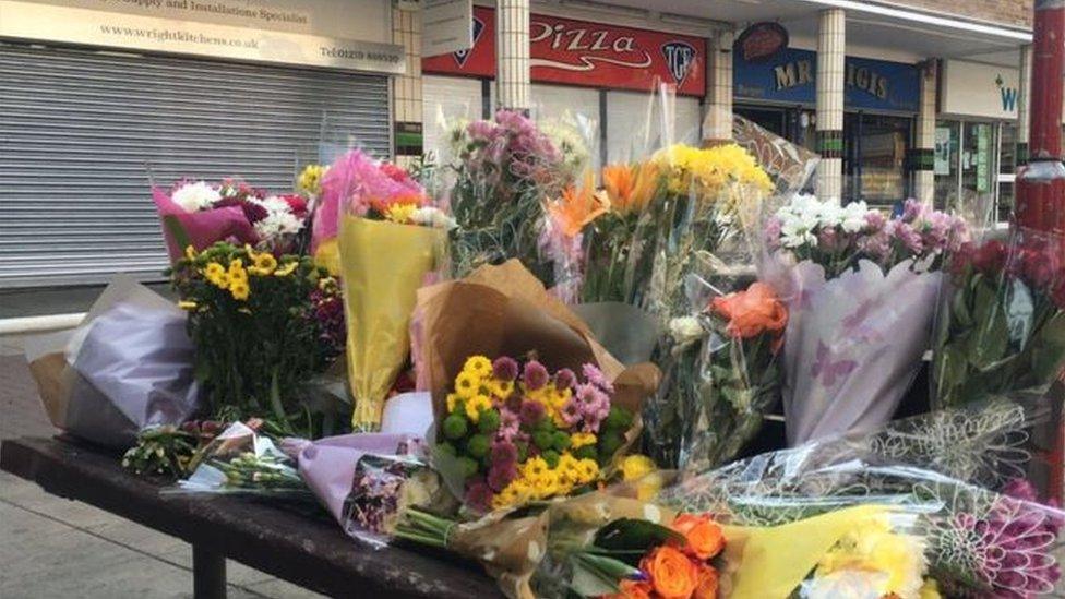 Flowers left near a row of shops in Harlow where a Polish man was attacked.