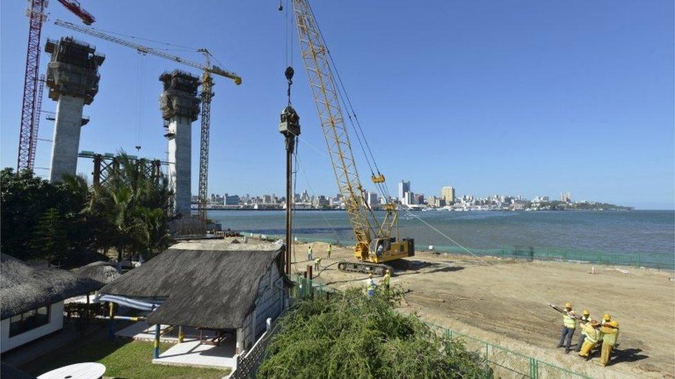 Construction workers build a new bridge against the skyline of Mozambique"s capital Maputo