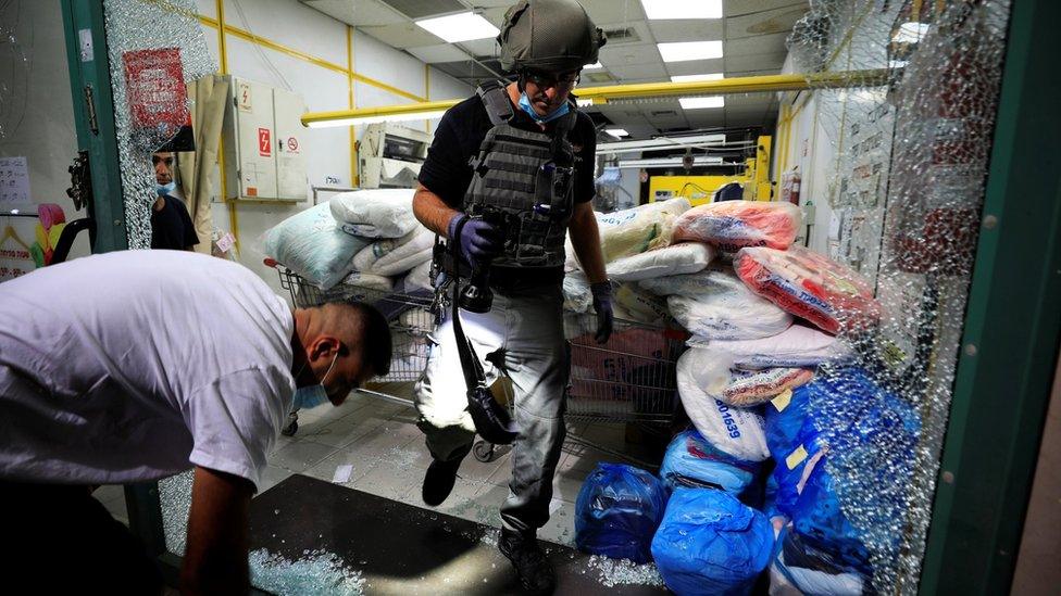 Israeli security personnel inspect a shopfront damaged in a rocket attack on the Israeli city of Ashdod (15 September 2020)