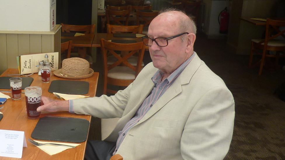 Vincent Stephens sitting at a pub table, holding a pint of bitter