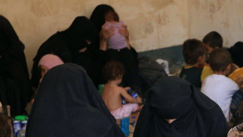 Families and relatives of suspected IS militants sit after surrendering to Kurdish Peshmerga forces in Ayadiya, Iraq (30 August 2017)