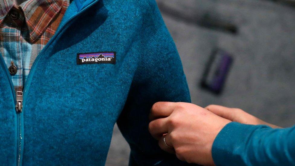 A member of staff adjusting a Patagonia jersey on a store mannequin