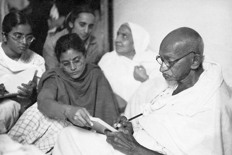 Gandhi dictating a message with help from Abha and Manu (far left) shortly after breaking his fast. Birla House. New Delhi. India. January 18, 1948