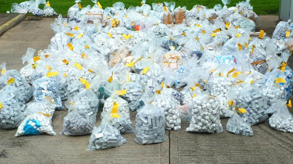 Dozens of big clear bags each stuffed full of little white bottles of drugs