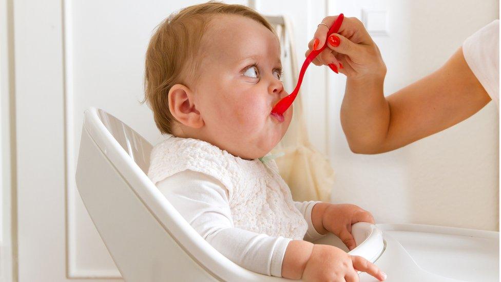 Baby being fed from a jar of baby food