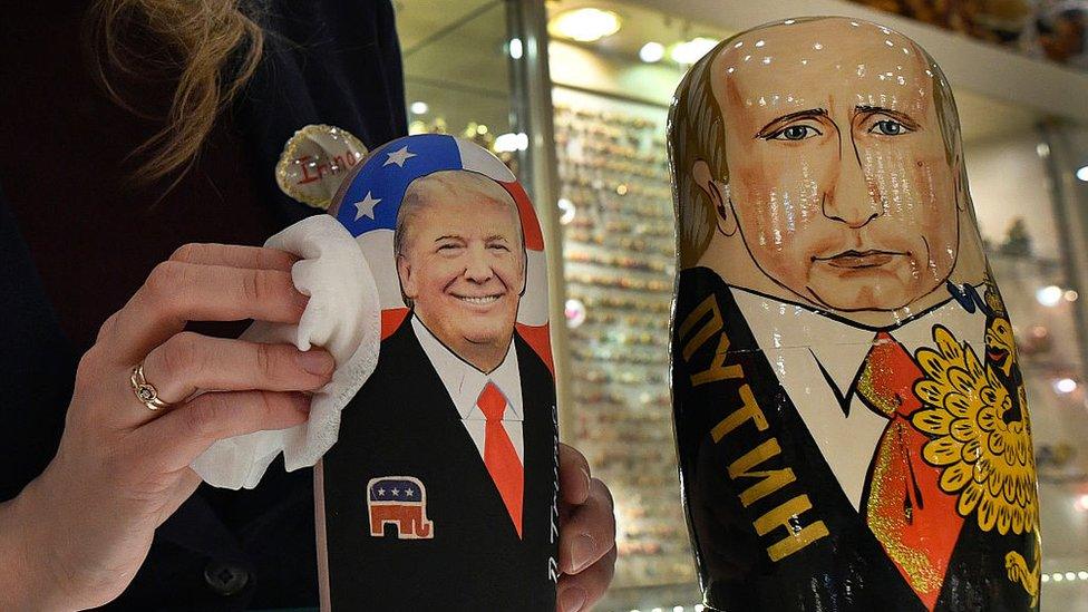 An employee polishes traditional Russian wooden nesting dolls, Matryoshka dolls, representing Donald Trump (L) and Vladimir Putin