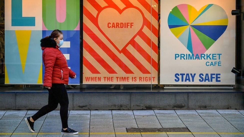 Woman walking past posters in Cardiff