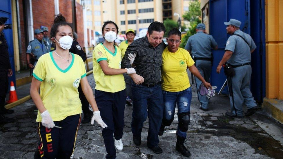 Rescuers help a victim at the ministry of treasury building during a blaze in San Salvador, El Salvador, July 7,