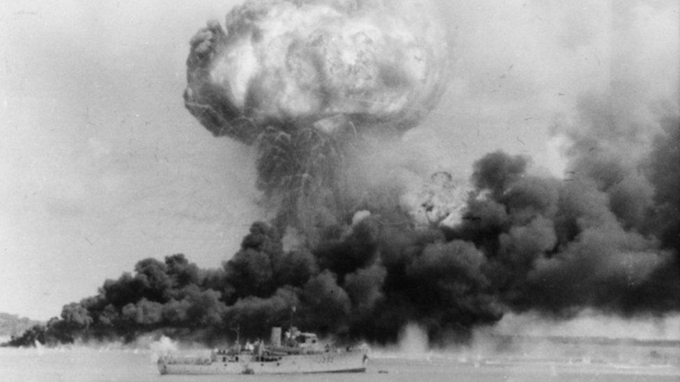 A ship in front of a plume of smoke