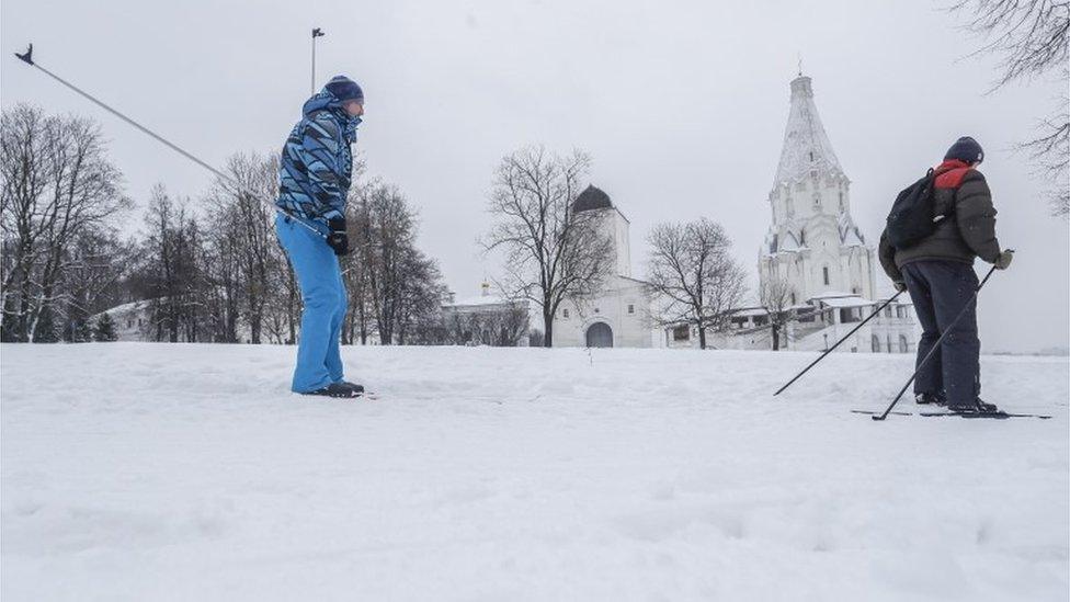 Men ski in front of the Ascension Church in Kolomenskoye park, a former Royal estate, during light snowfall in Moscow, Russia,