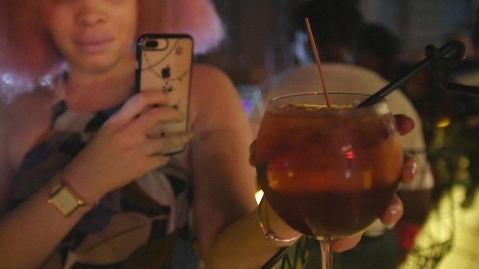 A woman photographing a cocktail in Lagos, Nigeria