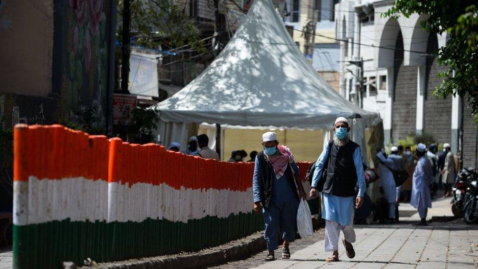 Men wearing protective facemasks walk to board a special service bus taking them to a quarantine facility amid concerns about the spread of the COVID-19 coronavirus in Nizamuddin area of New Delhi on March 31, 2020.