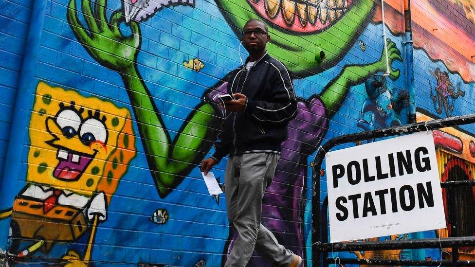 A voter walking passed a polling station sign