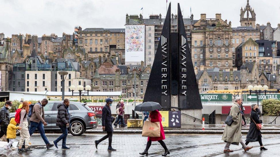 Commuters cross the street in front of the old town as showers and strong wind struck Edinburgh