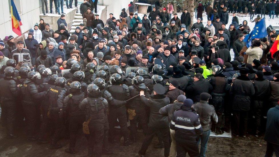 Protesters push a riot police line outside the parliament building in Chisinau, Moldova