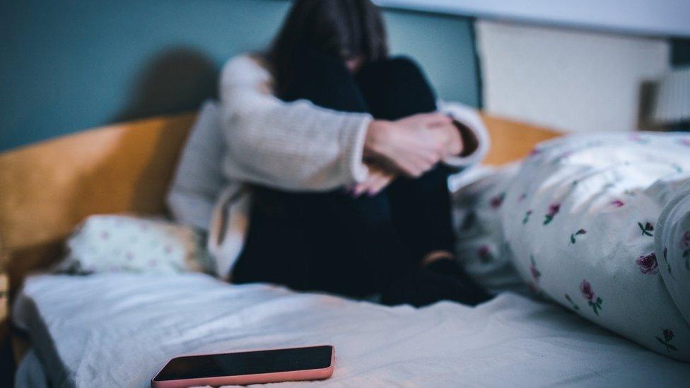 Girl holding her legs on a bed