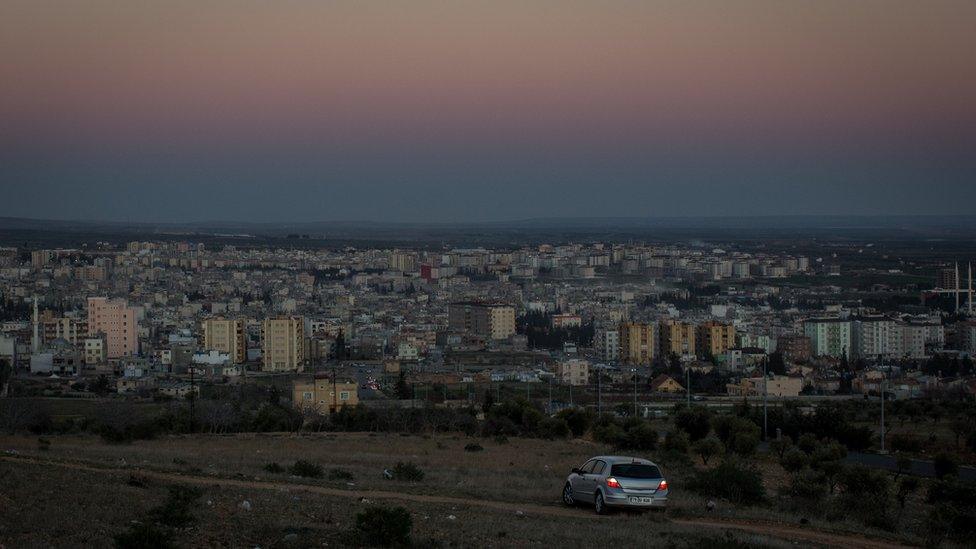 People watch the sunset from their car on a hill overlooking Kilis on March 1, 2016 in Kilis, Turkey