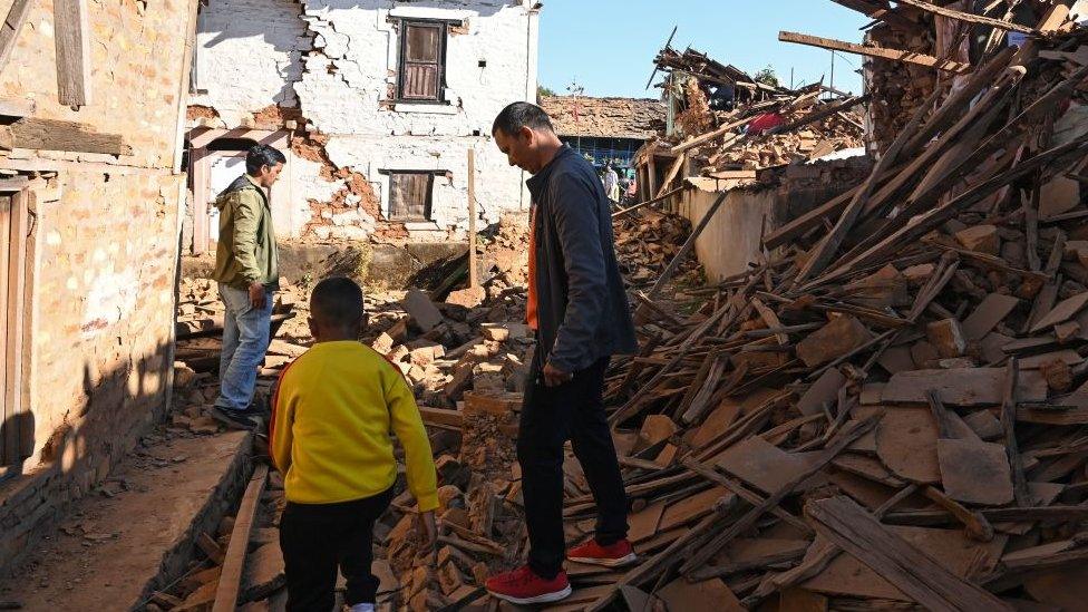 People walk through ruins of houses in the aftermath of an earthquake in Nepal