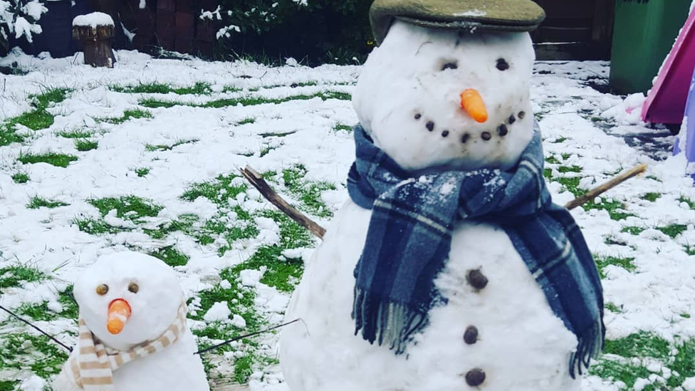 Two snowmen wearing hats and scarves.