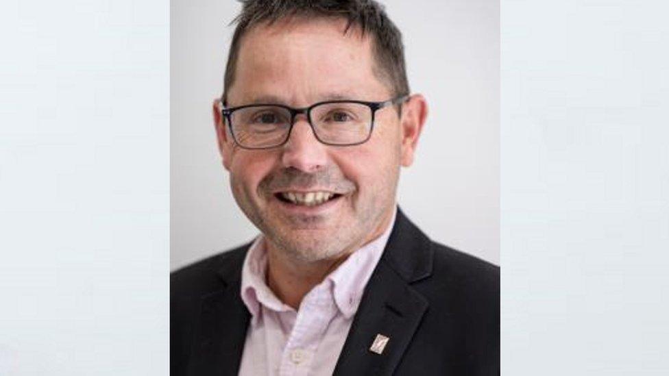 A white man in a pink shirt and jacket