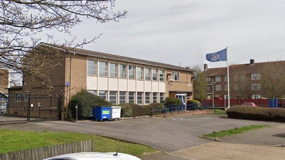 Brick-built two-storey police station with flag flying and car park