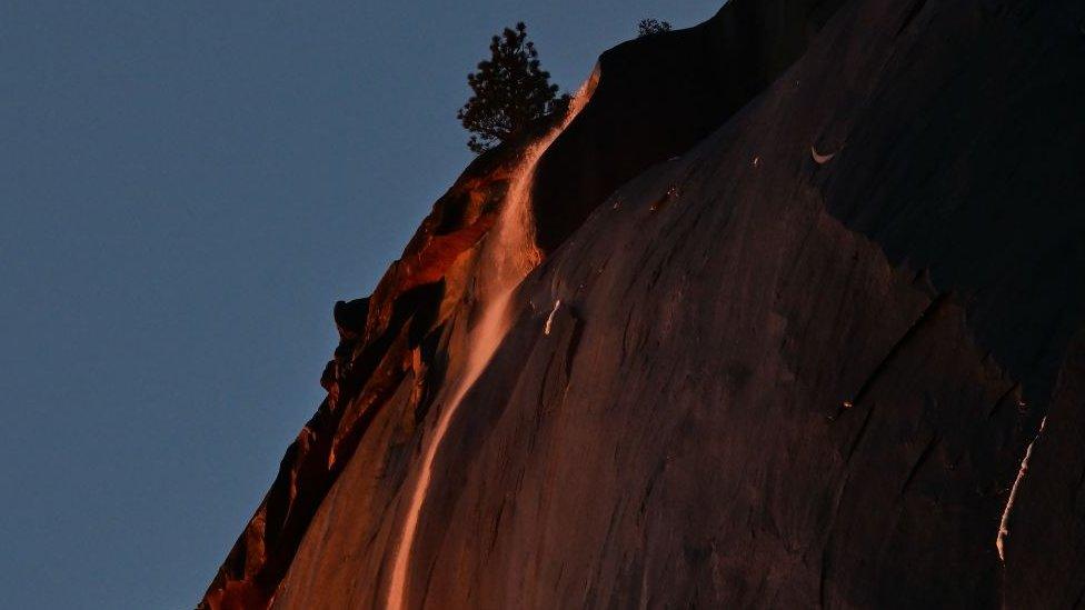 Water flowing off Horsetail Fall glows orange while backlit from the setting sun during the "Firefall" phenomenon in Yosemite National Park