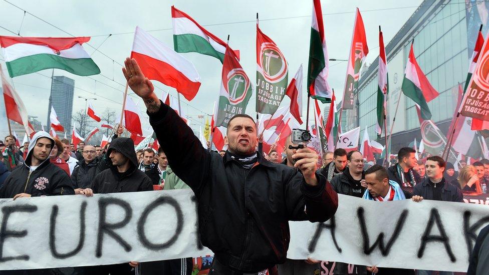 A demonstrator shouts and performs a Nazi salute in front of banner reading 'Europe awake' followed by a group of Hungarian Jobbik party representatives during an annual march commemorating Poland's National Independence Day in Warsaw on November 11, 2015