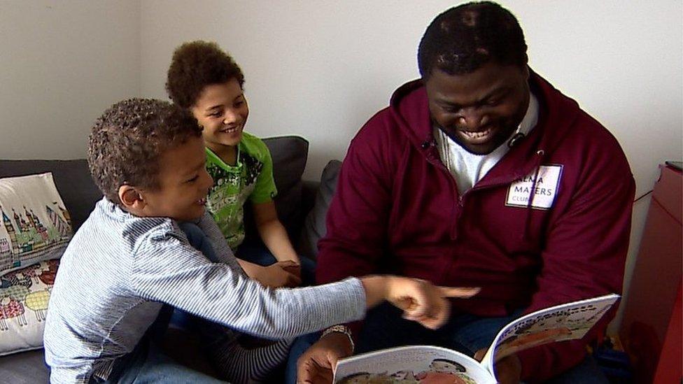 Suhmayah Banda reads a book with his sons