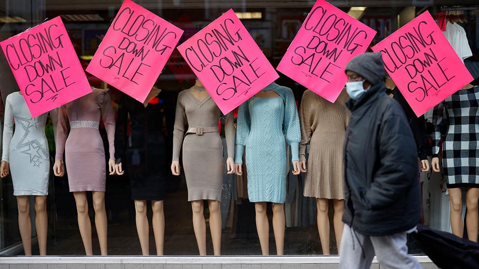 Person walking past shop which is closing down