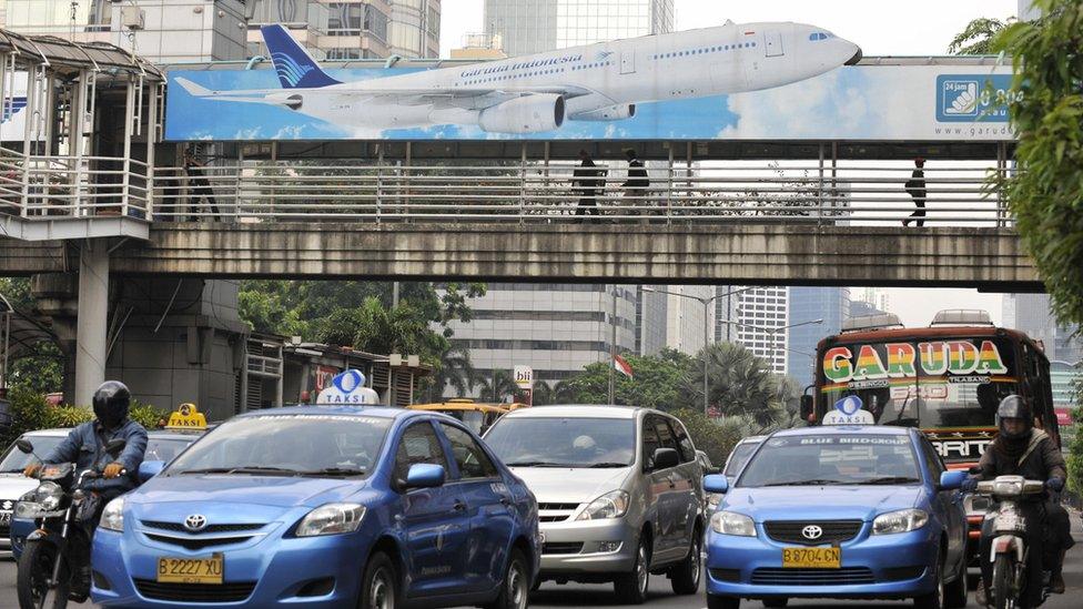 A billboard sits above a pedestrian bridge crossing a main road in Jakarta, Indonesia, 15 July 2009