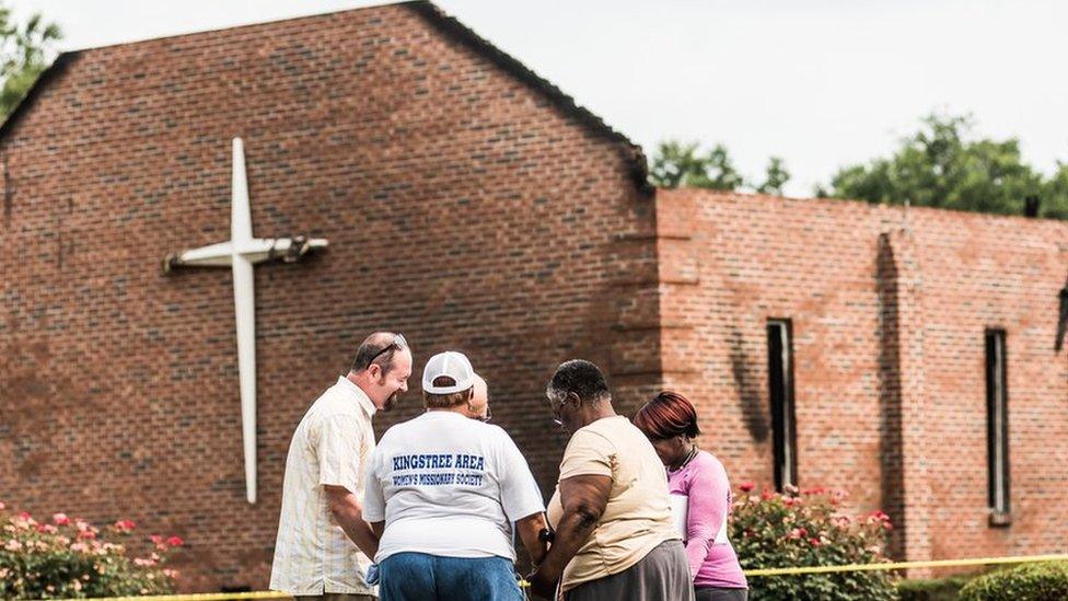 People pray near the burnt ruins of the Mt Zion AME Church in Greeleyville, South Carolina. Mt Zion was the seventh black church to burn in the southern US in less than two weeks