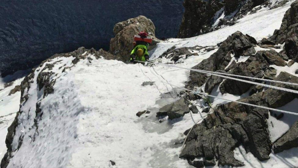 A climber using ropes to scale a steep, rocky section of K2