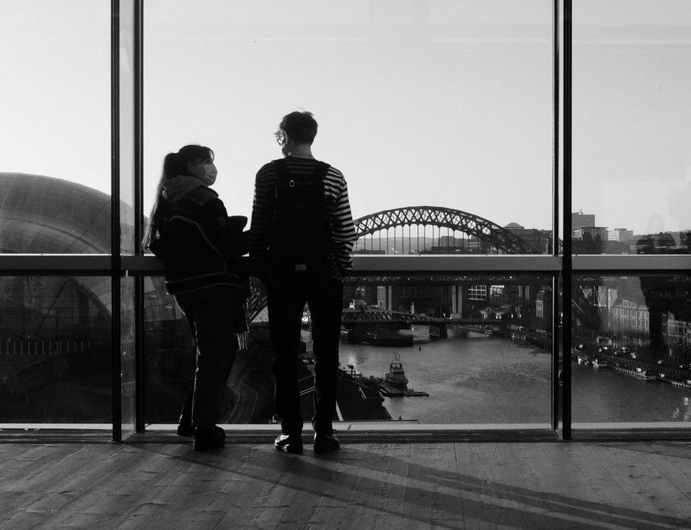 A couple look out of the window down on the Tyne bridge and Sage arts centre