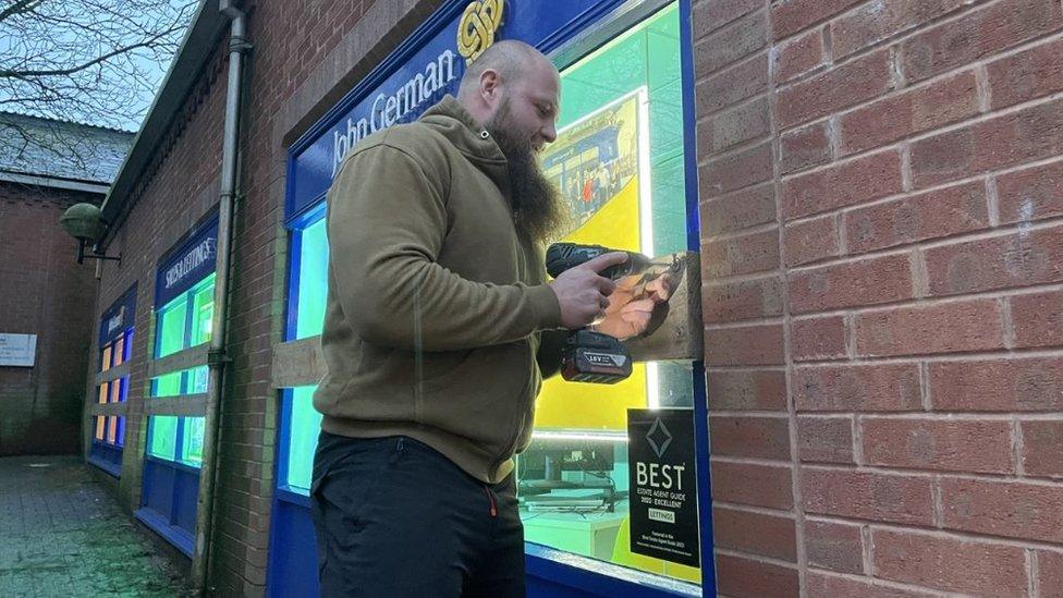 Man taking down barrier at shop