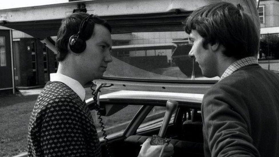 Matthew Price conducting an interview by the open boot of a car