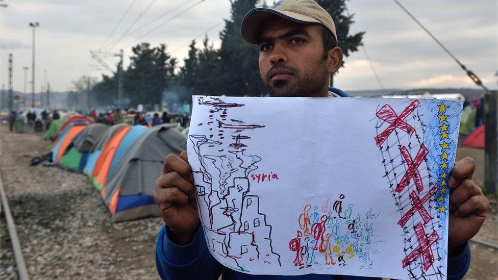 Migrant holds a drawing calling for the opening of the borders of EU countries