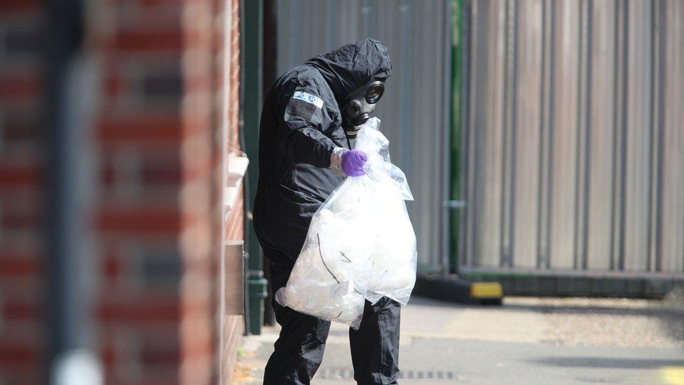 An investigator in a chemical suit removes items in connection with an alleged chemical attack in Salisbury