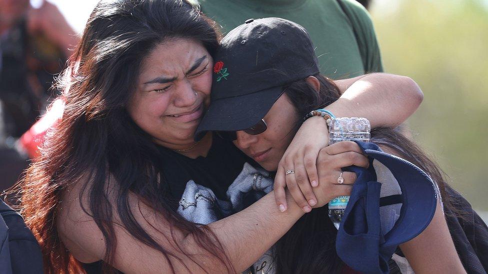 Fernanda Mora (L) an alumna from Deerfield Beach high school and Vallery Cruz a senior at the school hug in front of Marjory Stoneman Douglas High School, 23 February