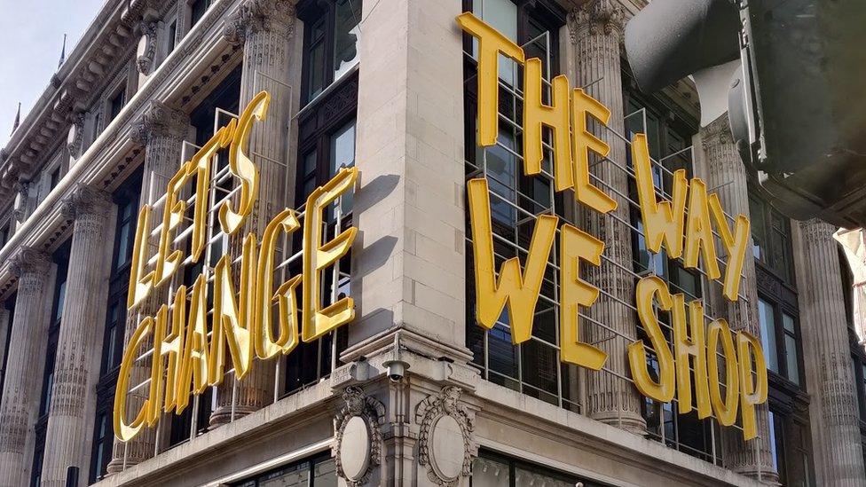 "Let's Change the way we shop" yellow sign onside of Selfridges building