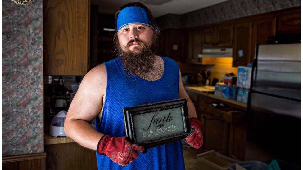 The first thing Adam did when he returned home is straighten the "Faith" sign above his door, creating a sense of normalcy and hope for what he faced. His home off of Greenwell Springs was overwhelmed with water. Denham Springs, LA.