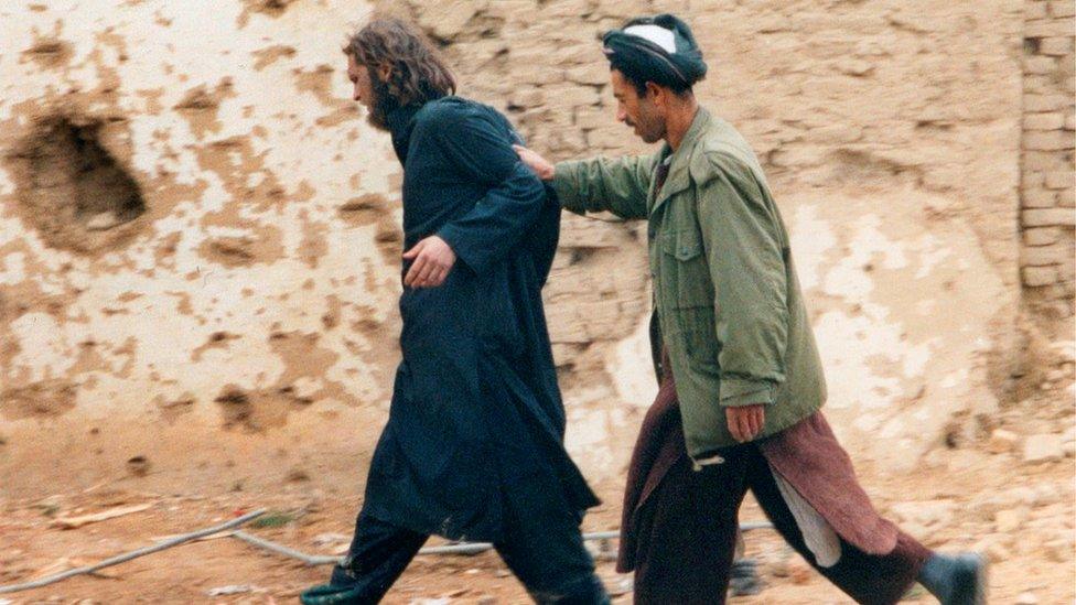 John Walker Lindh, left, photographed as he is captured by Northern Alliance Afghan forces in 2001