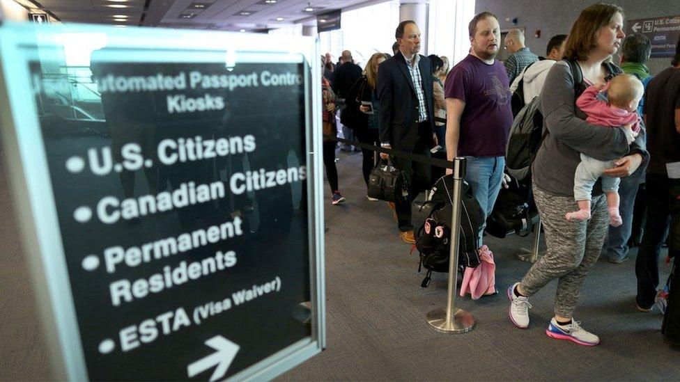 Passengers wait in line to use the Automated Passport Control Kiosks set up for international travelers arriving at Miami International Airport